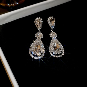 Macro shot of silver teardrop tassel earrings with sparkling crystals in a black gift box