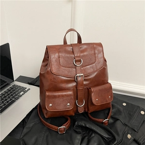 Vintage brown leather backpack with multiple pockets on black jacket and laptop