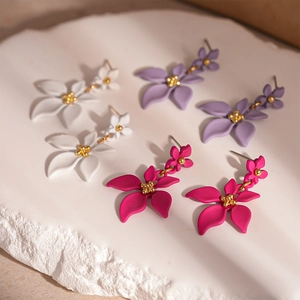 Boucles d'oreilles fleurs élégantes en blanc, violet et rose sur un socle en pierre
