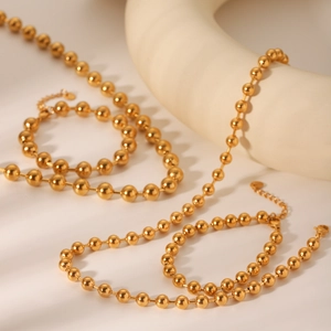 Polierte goldene Kugelkette mit Karabinerverschluss und elegantem Schattenspiel am Detail