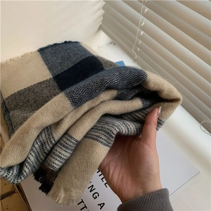 Detail shot of a thick blue checkered knit scarf with fringe on a magazine background