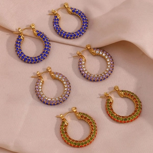 Detailed macro of gold hoop earrings with multi-colored rhinestones on silk fabric
