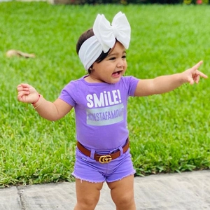 Close-up of baby purple floral t-shirt with shorts and a white bow headband set