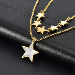 Detailed view of a gold double-layer star necklace on premium black leather texture