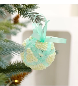 Close-up of mint green macaron foam Christmas ball with textured granules on tree branch