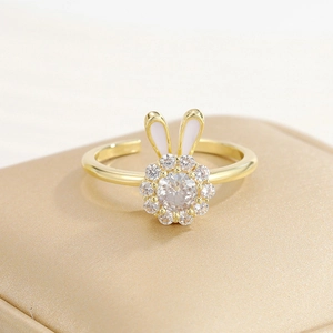 Detailed close-up of golden bunny ear open ring with zircon flowers and white enamel detail