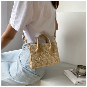 Detail of summer straw crossbody bag with floral embroidery and PU leather handles