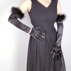 Detail of elegant black long satin gloves with feather trim and smooth texture
