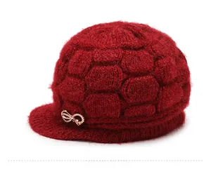 Detail of red knit visor hat with honeycomb texture and gold rhinestone butterfly accent