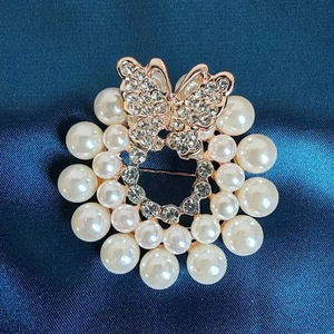 Macro shot of a butterfly brooch with rhinestones and faux pearls on blue satin