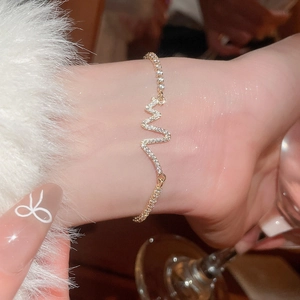 Close-up of heart rate zigzag gold bracelet with pavé cubic zirconia on woman wrist