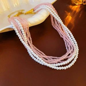 Detail of bohemian layered pearl necklace with pink crystal beads and golden clasp