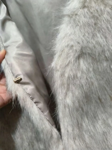 Close-up of light gray faux fur vest featuring soft plush fabric and hidden metal hook closure