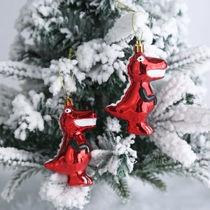Adornos navideños de dinosaurios rojos metálicos colgados en una rama nevada