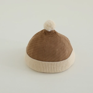 Detail of baby corduroy beanie featuring a plush pom-pom and ribbed knit fold-over brim