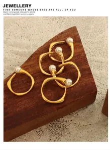Detail of five vintage gold-plated open rings with white pearls on a dark wood background