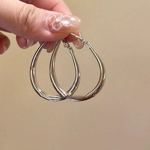 Minimalist silver twist hoop earrings with a glossy teardrop design for a modern look