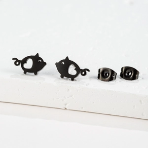 Macro detail of matte black cartoon pig stud earrings with hollow heart shape cutouts