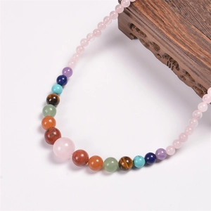 Detail of bohemian seven chakra necklace with natural pink quartz and multi-color stones