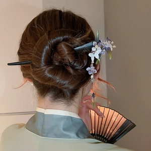 Detail of traditional Chinese hair stick with purple flowers and tassels in a bun
