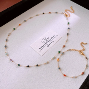 Detailed shot of golden necklace and bracelet set featuring colorful round beads