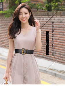 Detail of a wide black elastic waist belt with gold buckle on a lace dress for women