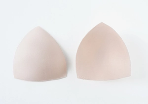Detailed macro view of beige triangular bra pads with soft seamless edges and logo