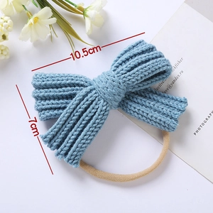 Detail shot of a blue knitted bow headband showing 10.5cm width and ribbed fabric texture
