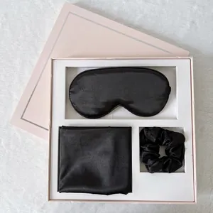 Detail view of a black silk sleep set with eye mask and scrunchie in a gift box