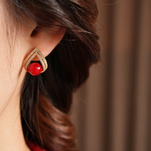 Vue macro de boucles d'oreilles triangle plaquées or 18 carats avec perle rouge et zircon
