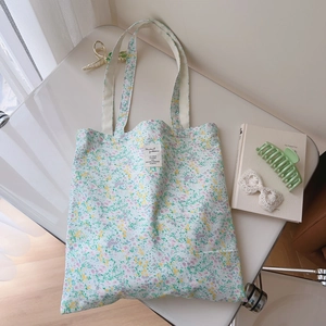 Close-up of cotton tote bag with floral pattern, white fabric label and long shoulder strap