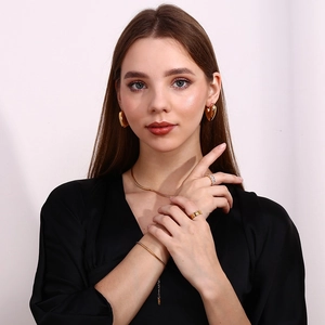 Polished 18K gold-plated jewelry set featuring heart earrings, necklace, and bracelet on model