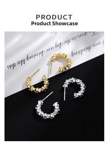 Detailed view of C-shaped silver and gold stud earrings with textured crushed metal finish