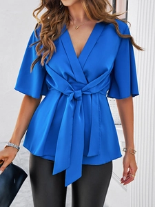 Détail du chemisier bleu à col en V avec taille nouée et manches mi-longues élégantes
