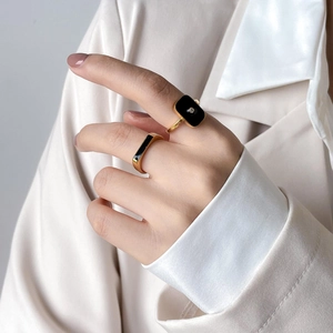 Close-up of elegant gold and black enamel ring set with crystal accents on a hand