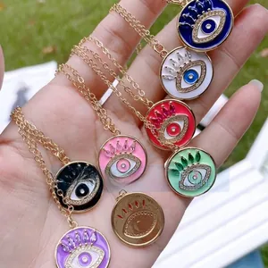 Nahaufnahme bunter Evil-Eye-Anhänger mit Emaille-Finish und Goldketten in der Hand