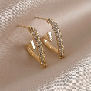 Detailed close-up of gold-plated C-shaped earrings with zircon heart details on silk
