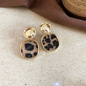 Close-up of retro leopard print square pendant earrings with golden metallic studs