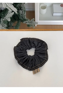 Close-up of navy denim scrunchie with yellow stitching and decorative Dream fabric label