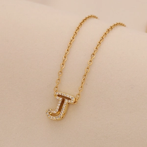 Close-up of golden necklace featuring a crystal-encrusted letter J pendant on a fine chain