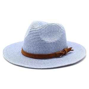 Detail of light blue straw panama hat featuring a brown suede band and tassel buckle