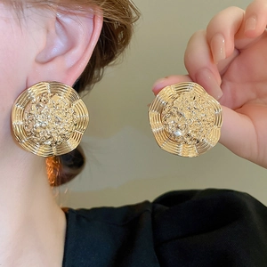 Detail of gold oversized irregular geometric earrings with hammered texture on a model