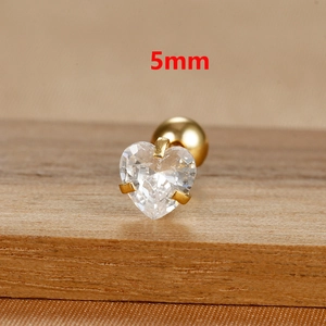 Macro shot of 5mm heart-cut zircon stud earring with gold finish on wooden texture