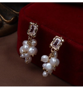 Detail of baroque pearl grape cluster earrings with gold-plated metal and zircon stone