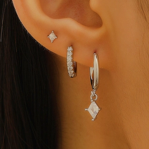 Silver earring set with rhombus zircon studs and pavé hoops shown on ear model