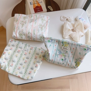 Detailed close-up of three floral cotton makeup bags with simple wish label on table