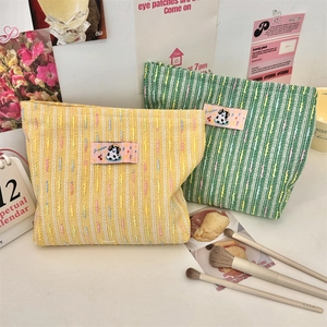 Détail d'une trousse de maquillage en tweed avec écusson vache et texture tissée