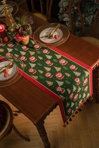 Detail of green Christmas table runner featuring jacquard Santa Claus and festive tassels