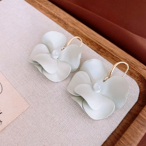 Close-up of matte mint green and cream flower earrings with golden hooks and white beads
