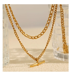 Vue détaillée du collier doré avec fermoir OT suspendu sur des verres décoratifs